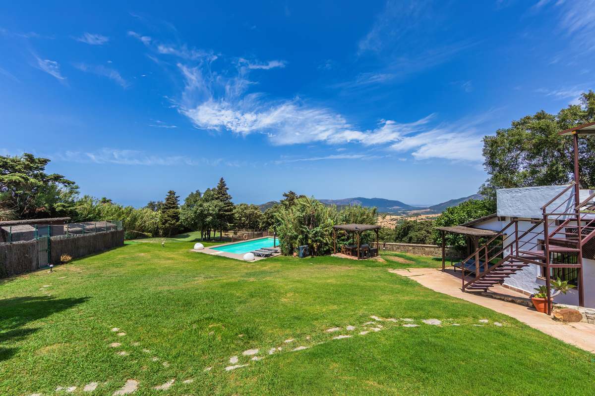 Jardín amplio con piscina y porche de madera con vistas a las montañas de Tarifa