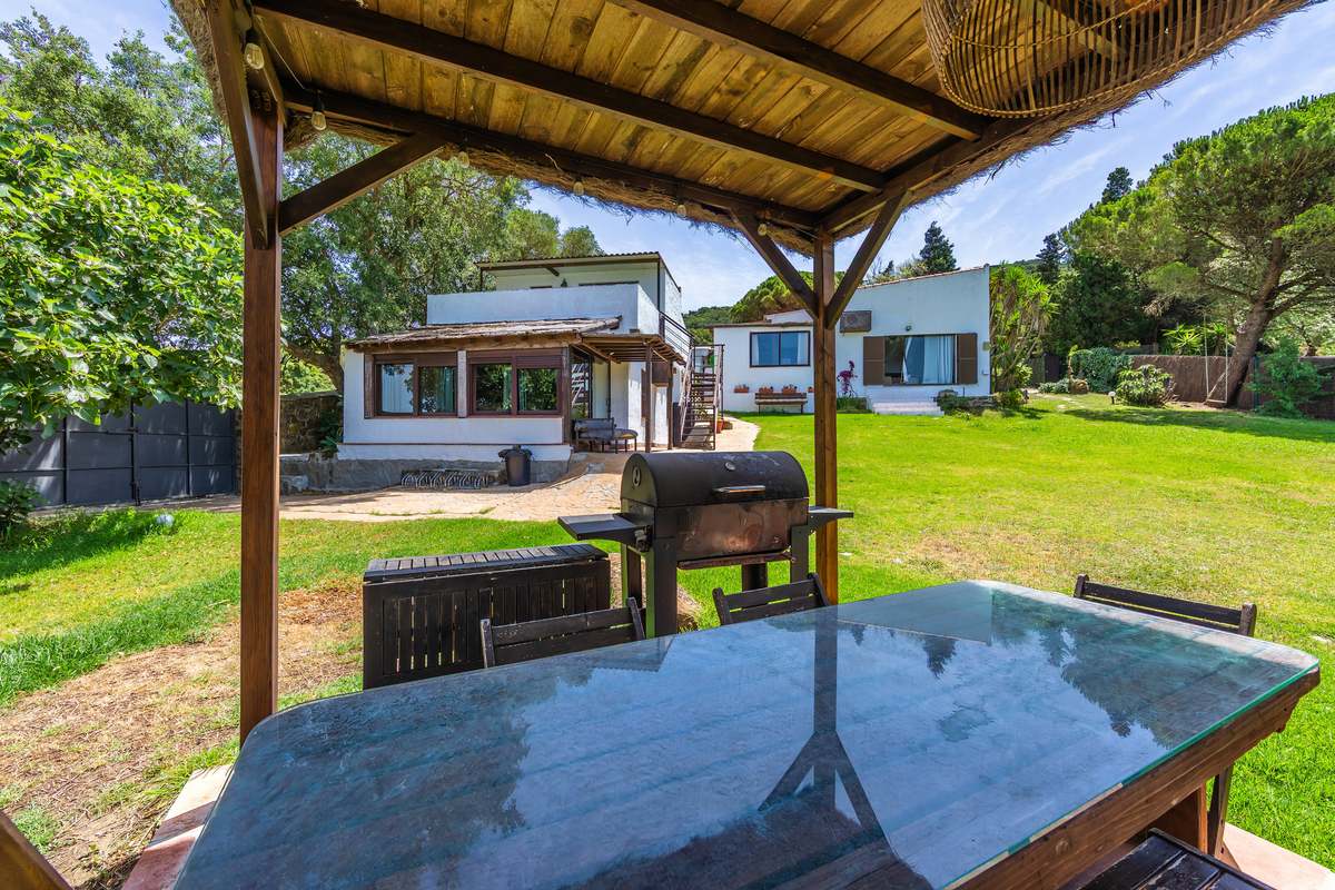 Porche con mesa de cristal, barbacoa y vistas al jardín de la casa en Tarifa
