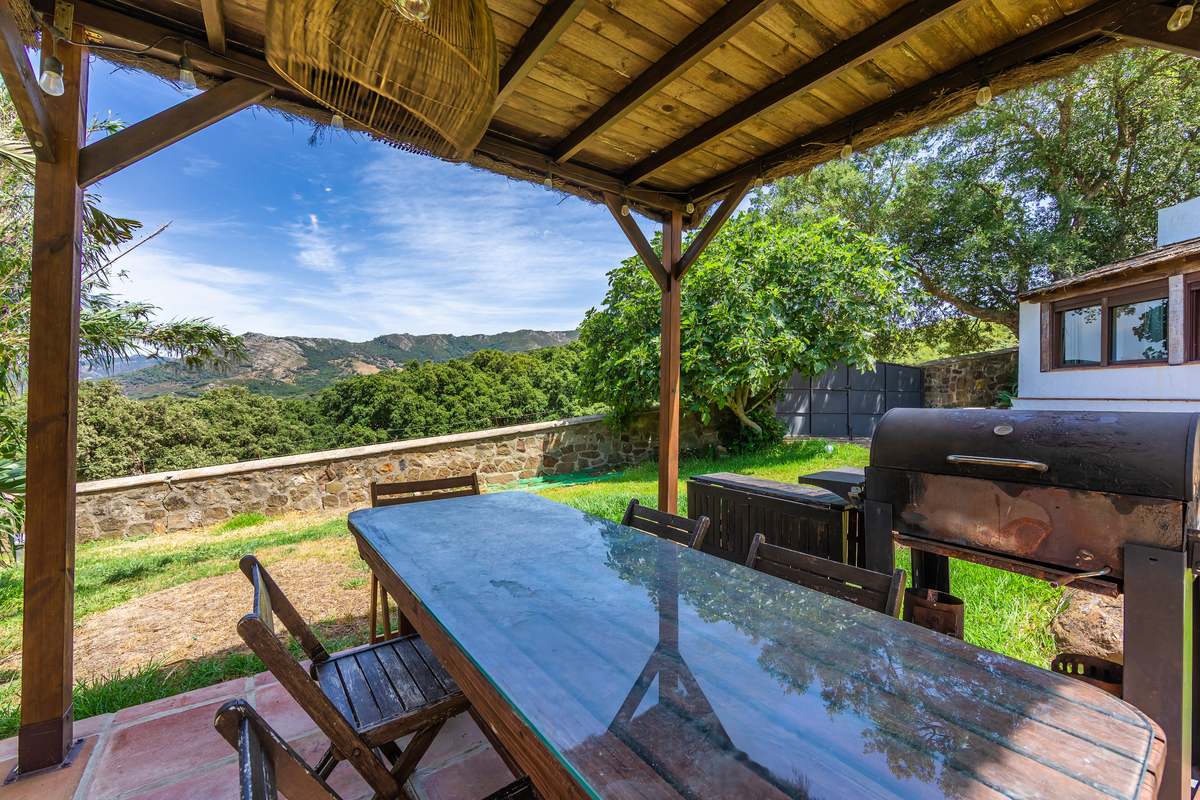 Porche con mesa de cristal y ahumador en jardín con vistas a las montañas de Tarifa