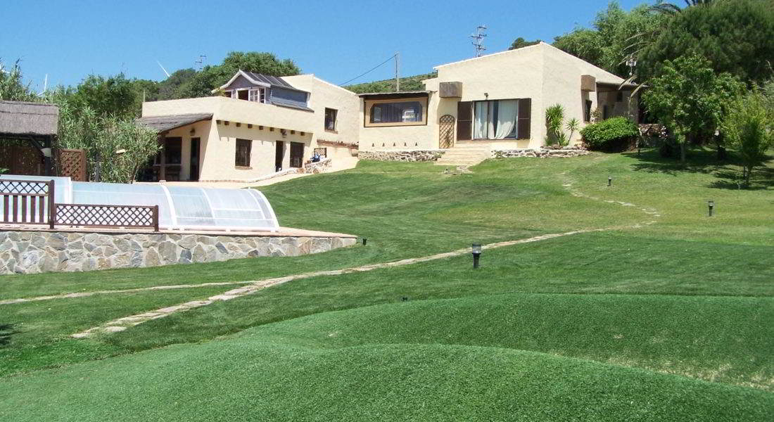 Chalet con piscina cubierta rodeado de un amplio jardín con césped bien cuidado en un entorno tranquilo y natural.