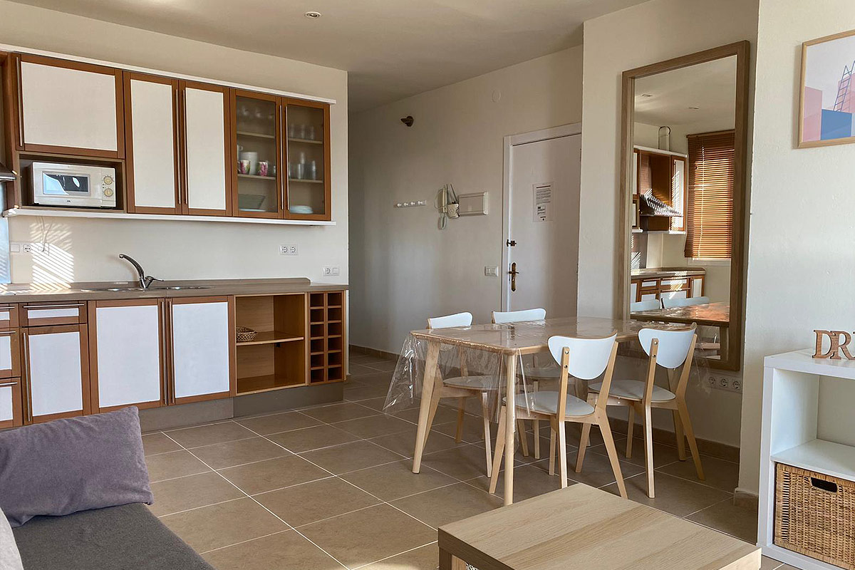 Cocina abierta con comedor, mesa de madera y detalles modernos.