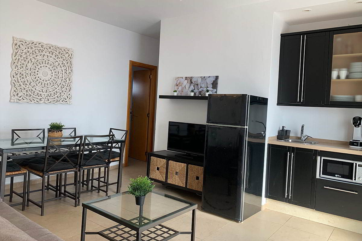 Cocina y comedor del apartamento Freedom, combinando muebles modernos negros y electrodomésticos.