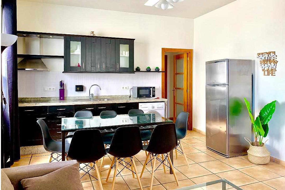 Cocina moderna con comedor amplio en el apartamento Wellness, equipada con electrodomésticos y decoración funcional.