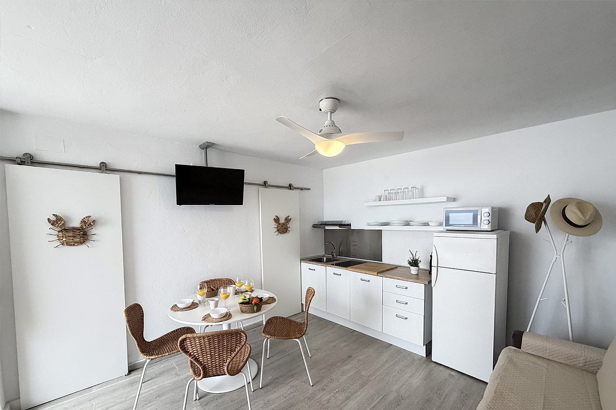 Cocina abierta con comedor y zona de estar en apartamento Infinity en Tarifa.