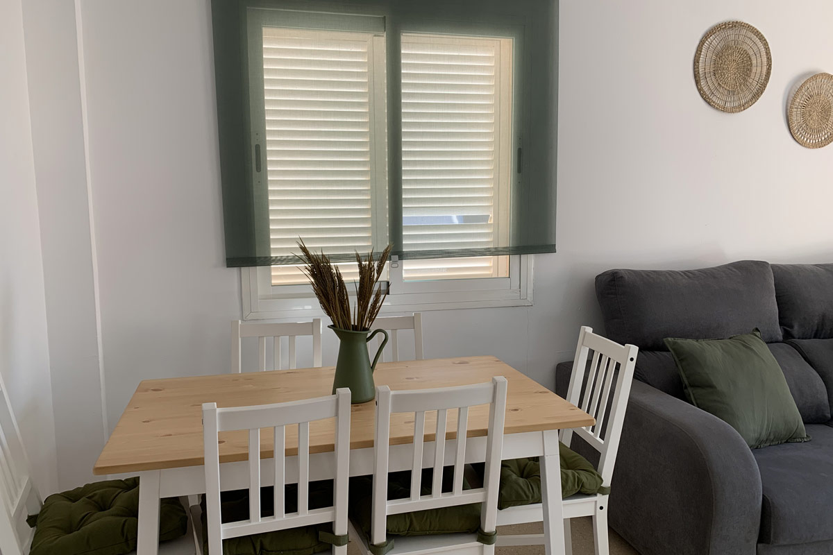 Salón de Los Lances 2 con zona de comedor, sofá chaise longue y decoración en tonos verdes y naturales.