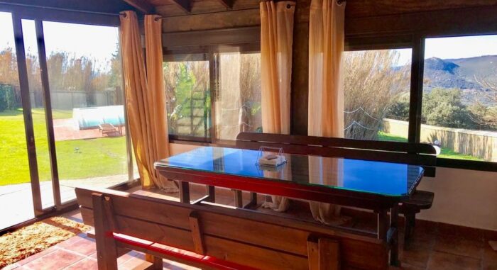 Comedor en la casa de invitados del Chalet La Ahumada con mobiliario de madera, vistas al jardín y un entorno luminoso.