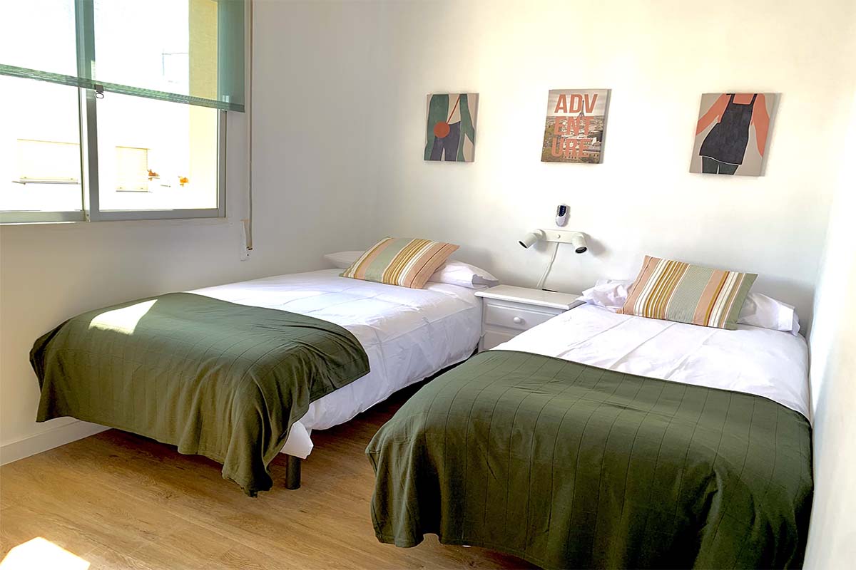 Dormitorio con dos camas individuales y ropa de cama verde oliva.