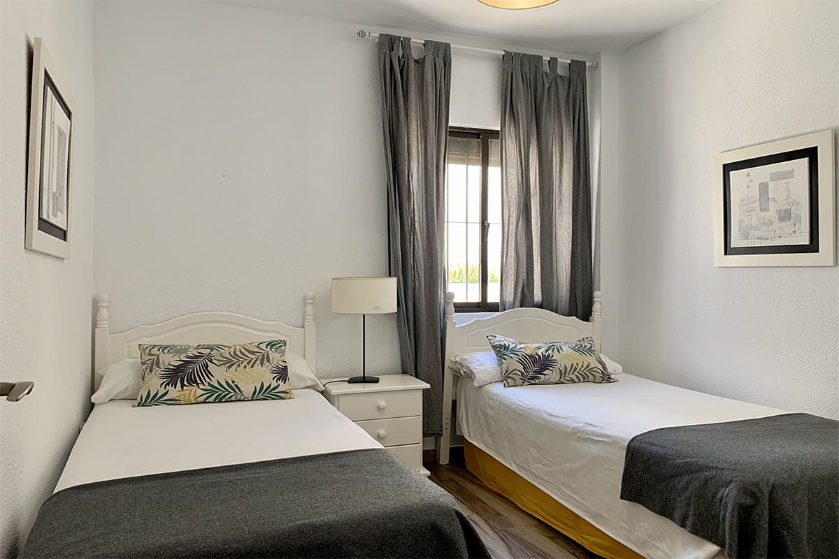 Dormitorio con dos camas individuales, decorado en tonos grises.