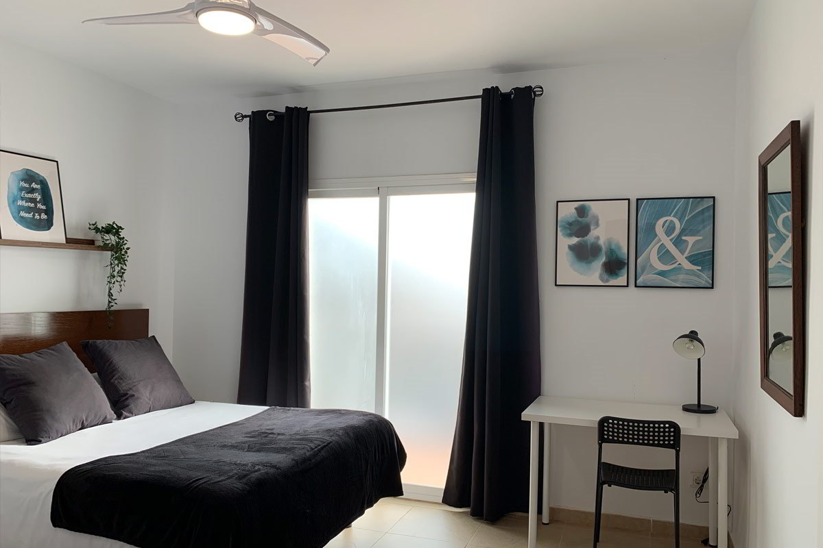 Dormitorio luminoso con escritorio en el apartamento Freedom, decorado con tonos oscuros y detalles modernos.