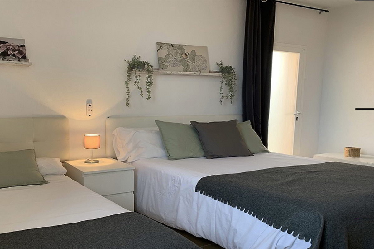 Dormitorio principal del apartamento Freedom en Tarifa, con dos camas, decoración minimalista y detalles en tonos grises y verdes.