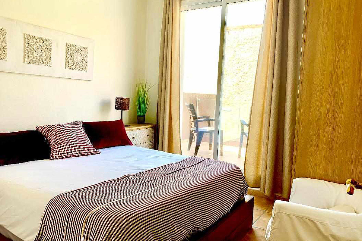 Dormitorio principal del apartamento Wellness con cama doble, decoración cálida y acceso a la terraza.