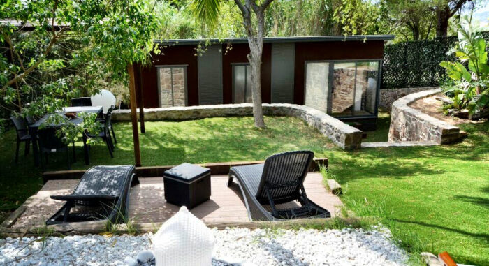 Jardín de la Villa Nepal con zona de descanso, tumbonas, mesa de exterior y rodeado de naturaleza.