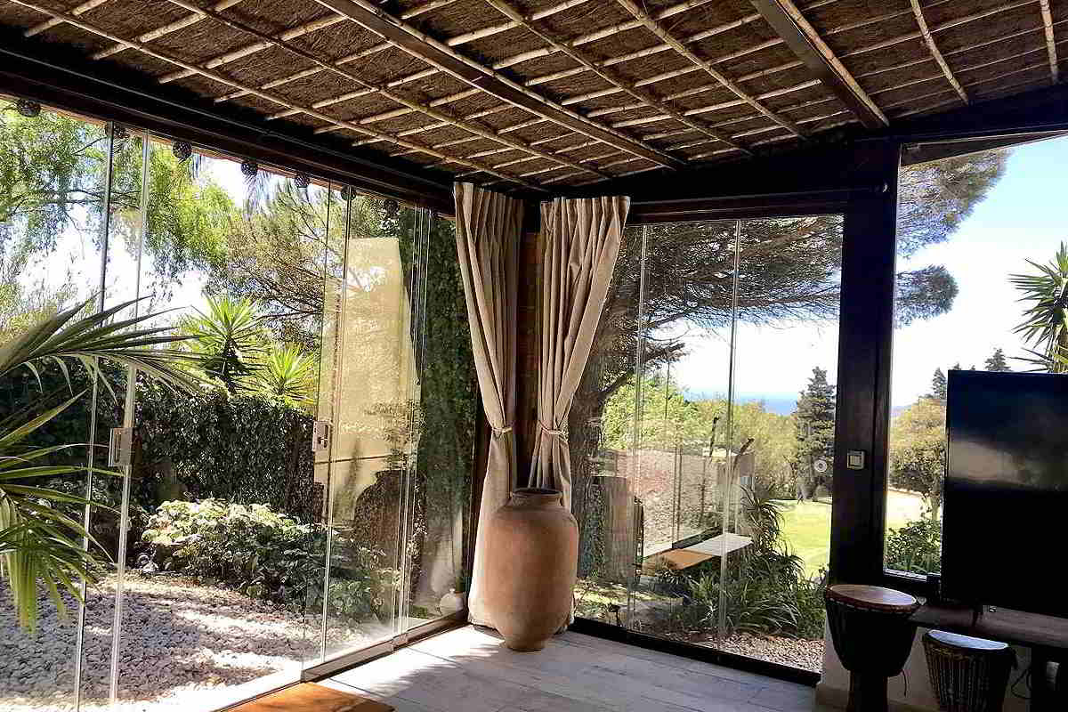 Jardín del chalet La Ahumada con vistas al mar, rodeado de vegetación y árboles.