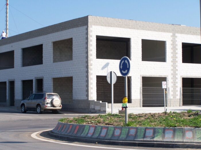 Edificio en construcción de locales comerciales en una rotonda de Tarifa con diseño moderno y estructura funcional.