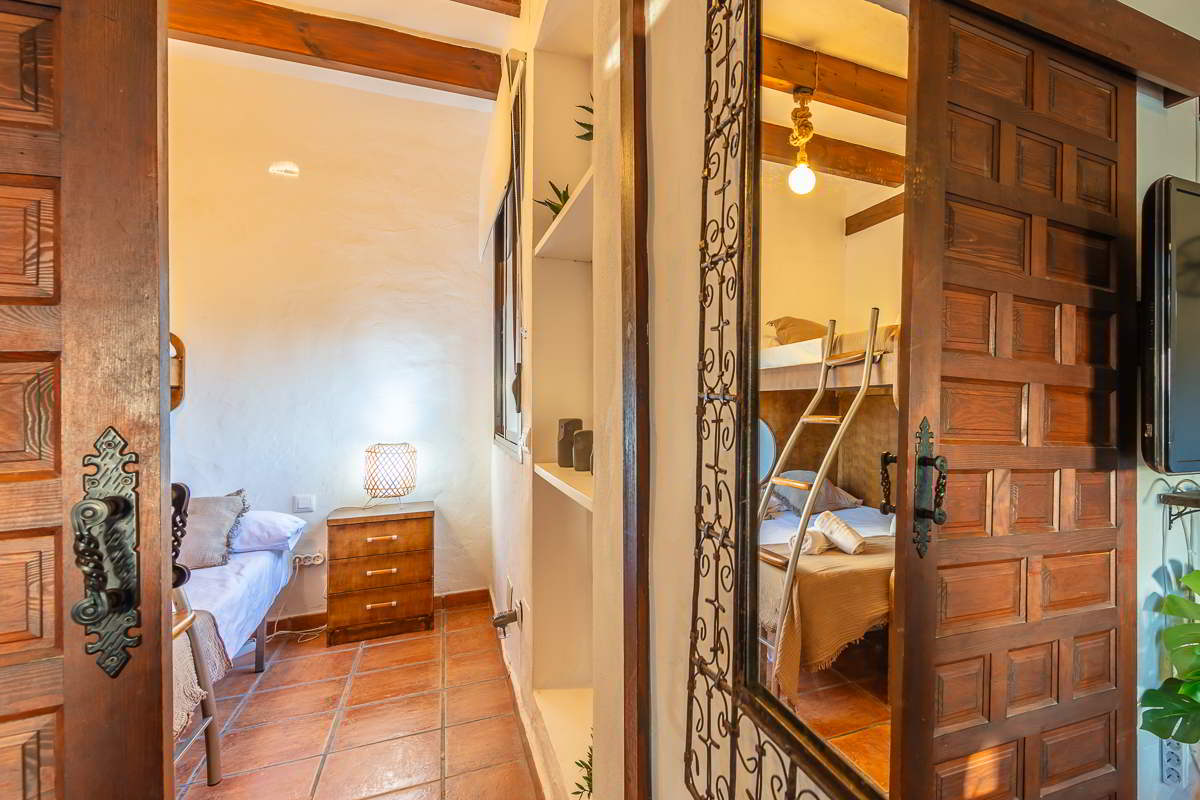 Vista de dos dormitorios de Villa Paraíso en Villas La Ahumada, Tarifa, uno con cama individual y otro con litera metálica, vistos desde el salón