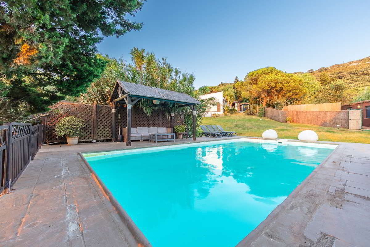 Piscina de Villa Paraíso con zona chill out y vistas al jardín en Villas La Ahumada, Tarifa.