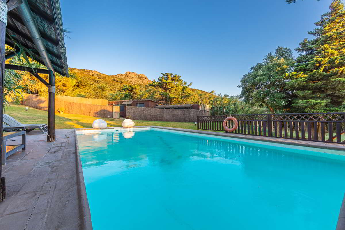 Piscina de Villa Paraíso con vistas a la montaña y zona ajardinada en Villas La Ahumada, Tarifa.