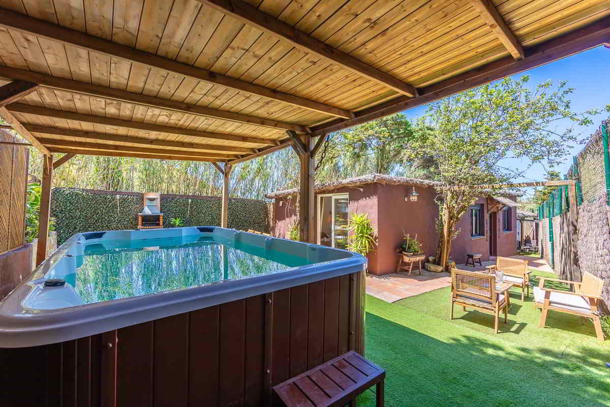 Vista del jacuzzi techado de Villa Verde, con el jardín privado y zona de estar exterior al fondo, rodeado de vegetación y privacidad.