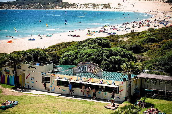 Playa de Valdevaqueros con chiringuito Tumbao, césped y ambiente de kitesurf.