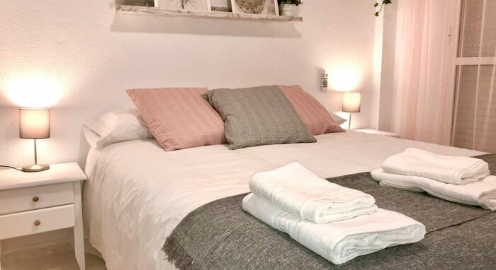 Dormitorio del apartamento Callao con cama doble, decoración en tonos suaves y lámparas cálidas a cada lado.