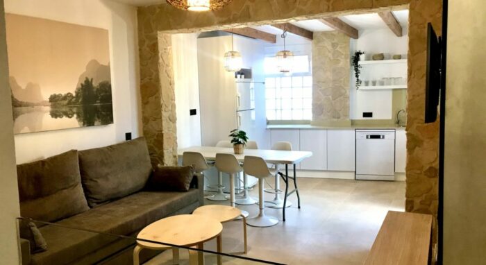 Salón del apartamento Las Gaviotas con sofá amplio, comedor y cocina abierta de diseño rústico moderno.