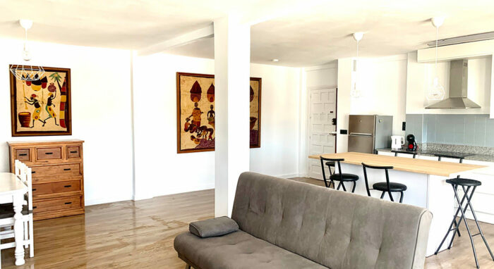 Salón del Apartamento Tinto con decoración moderna, sofá cama, cocina americana y comedor en un espacio amplio y luminoso.