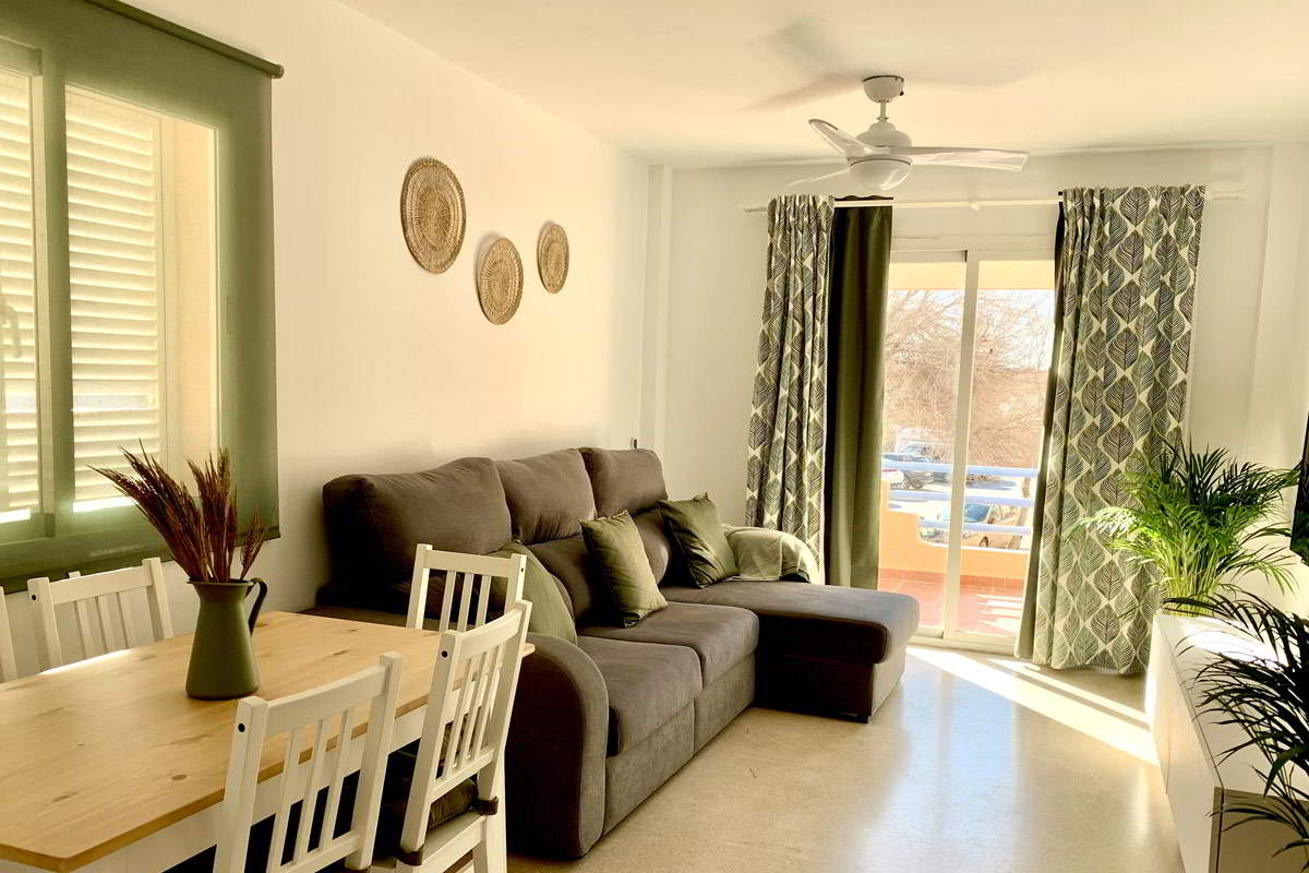 Salón de Los Lances 2 con zona de comedor, sofá chaise longue y decoración en tonos verdes y naturales
