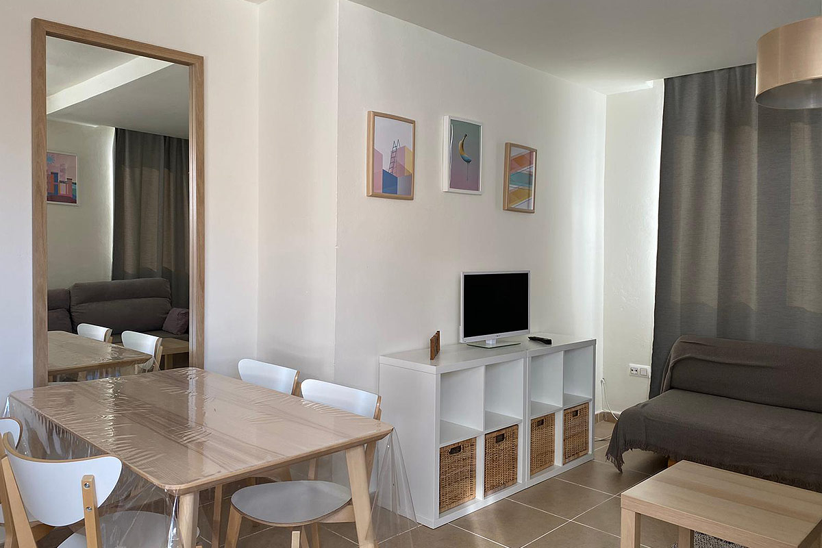 Salón con mesa de comedor, espejo y sofá con decoración minimalista.