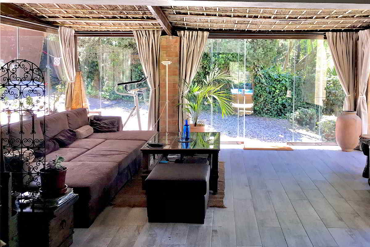 Salón del chalet La Ahumada con diseño rústico y acceso directo al jardín, lleno de luz natural y vegetación.