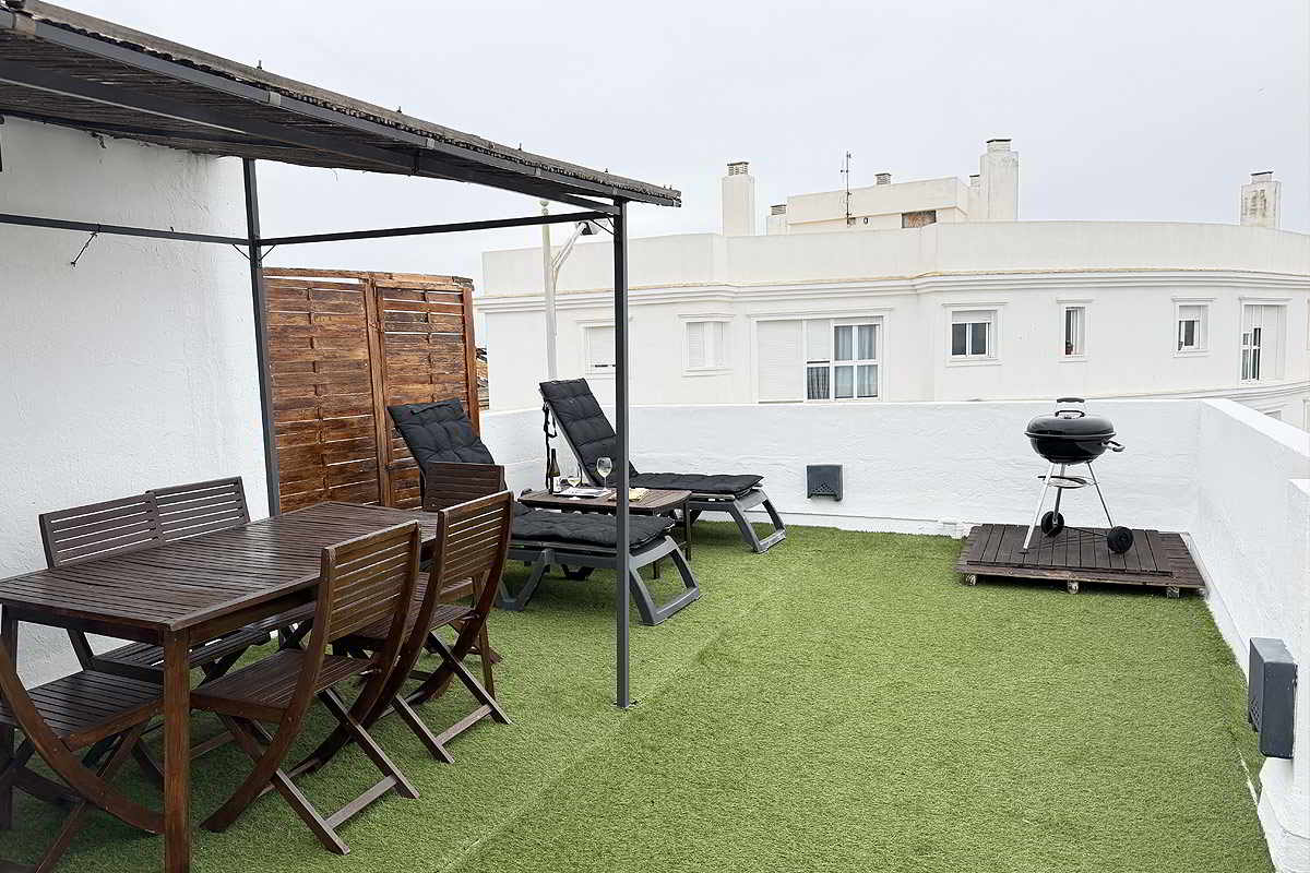 Terraza amplia con comedor exterior, tumbonas y barbacoa en apartamento Infinity.