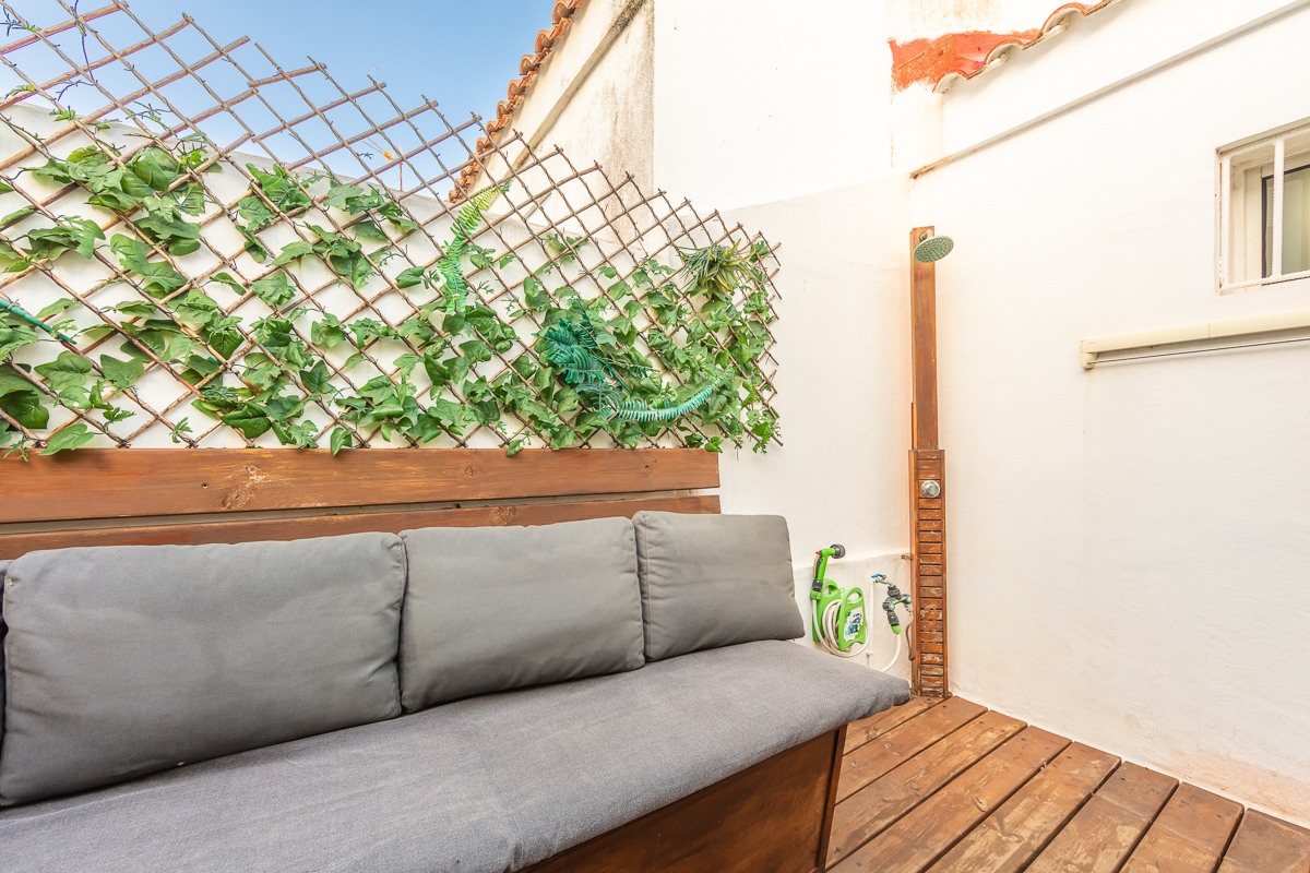 Zona chill out del Apartamento Las Gaviotas Nº9A con banco acolchado, suelo de madera y ducha exterior en terraza privada.