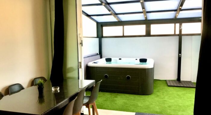 Terraza cubierta en el apartamento Las Gaviotas con jacuzzi, césped artificial y zona de comedor.