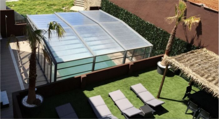 : Terraza del Edificio Senses con piscina cubierta, tumbonas, palmeras y zona de sombra en Tarifa.