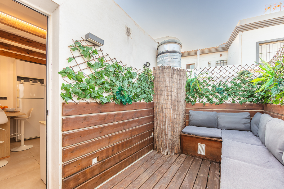 Terraza privada del Apartamento Las Gaviotas Nº9A con suelo de madera, banco con cojines y vegetación decorativa.