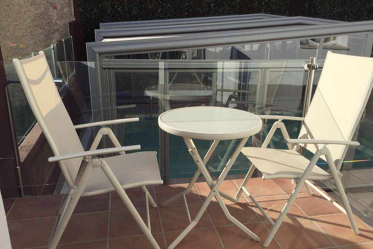 Terraza privada del apartamento Wellness con mesa y sillas, junto a la piscina cubierta.