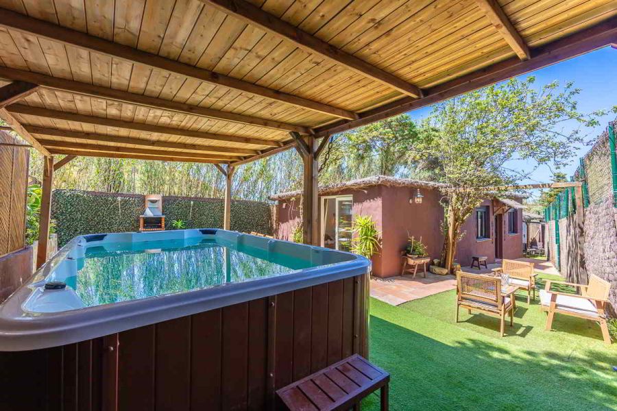 Vista del jacuzzi techado de Villa Verde, con el jardín privado y zona de estar exterior al fondo, rodeado de vegetación y privacidad.