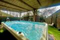 Jacuzzi exterior con cubierta de madera, agua burbujeante y jardín rodeado de naturaleza.