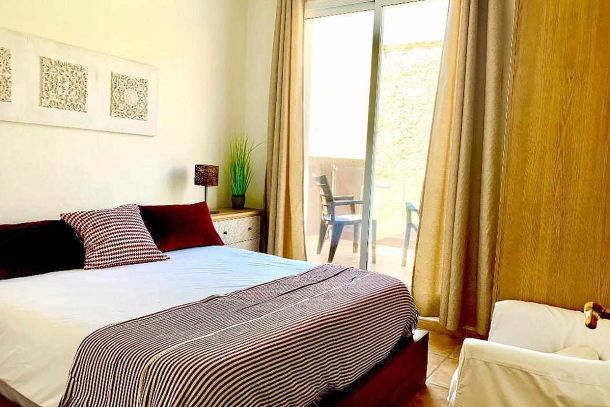 Dormitorio principal del apartamento Wellness con cama doble, decoración cálida y acceso a la terraza.