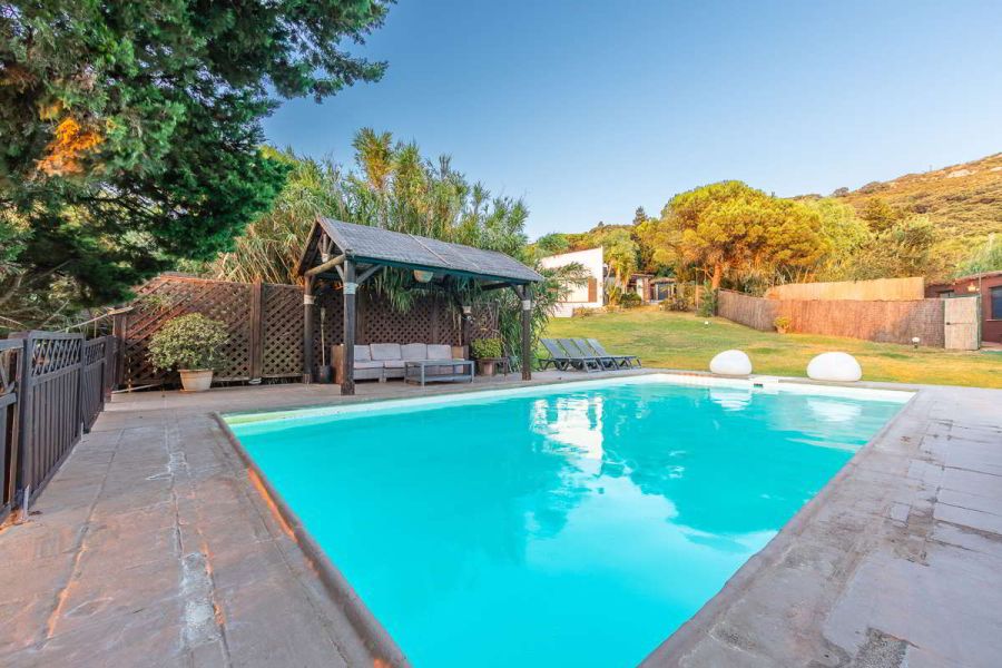 Piscina de Villa Paraíso con zona chill out y vistas al jardín en Villas La Ahumada, Tarifa.