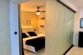 Vista de dormitorio principal con cama doble y pared divisoria corrediza de vidrio.