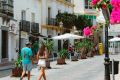 Calle céntrica de Tarifa con flores, terrazas y edificios blancos históricos.