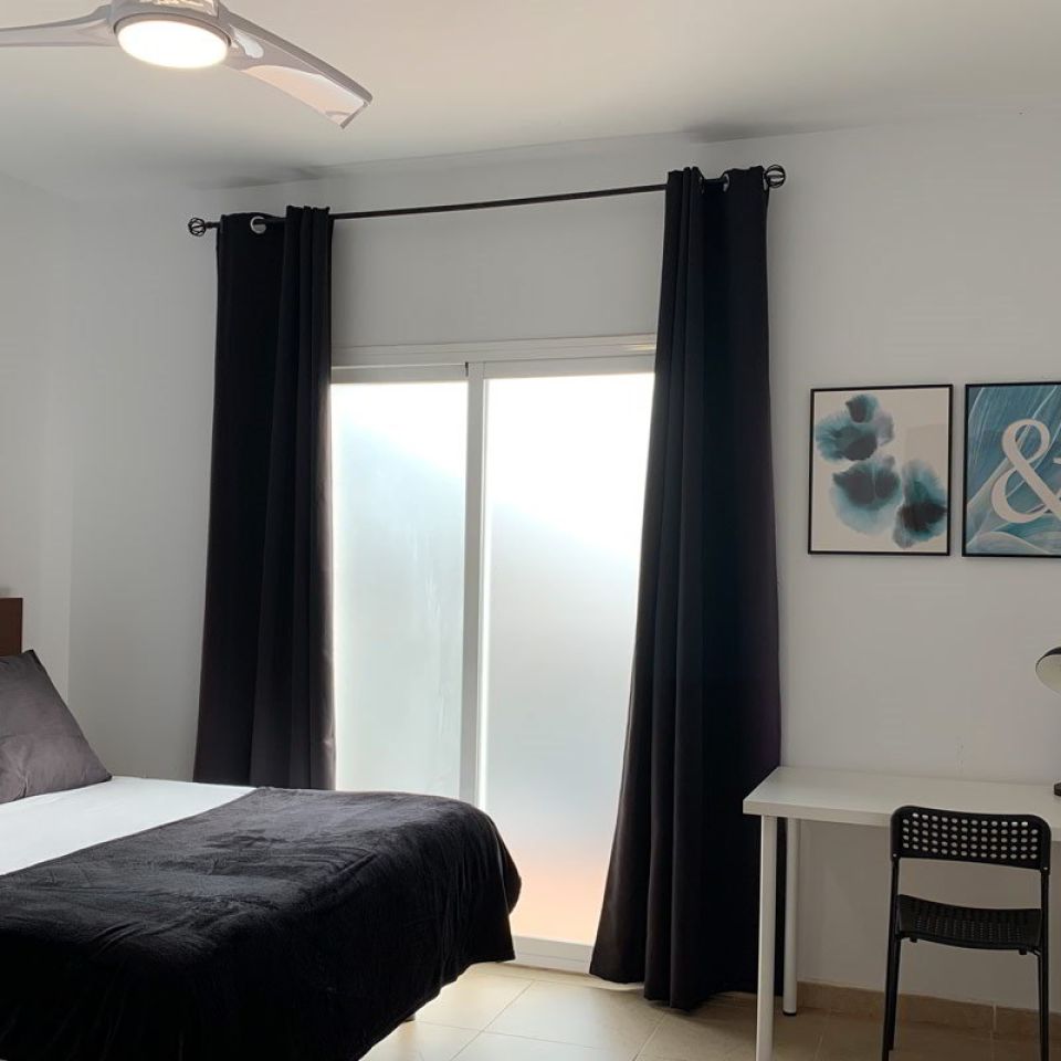 Dormitorio luminoso con escritorio en el apartamento Freedom, decorado con tonos oscuros y detalles modernos.