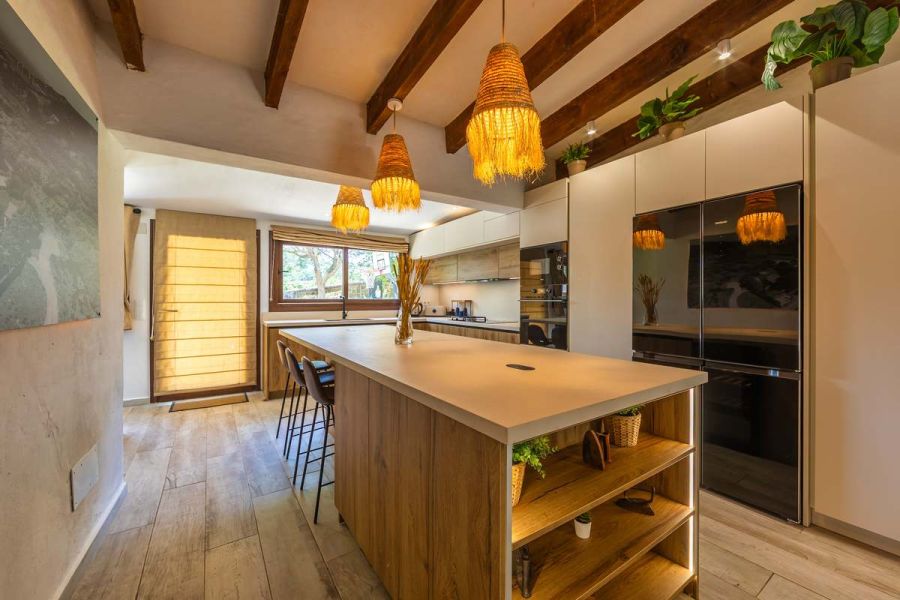 Cocina rústica con isla de madera, lámparas de mimbre colgantes y nevera de cristal negro