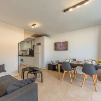Salón comedor luminoso del apartamento Las Gaviotas 9B en Tarifa con cocina abierta, mesa para cuatro personas y zona de estar integrada.
