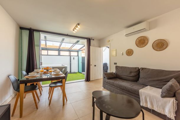 Salón comedor del apartamento Las Gaviotas 9B en Tarifa con sofá, mesa de comedor y vistas directas al patio con jacuzzi privado.