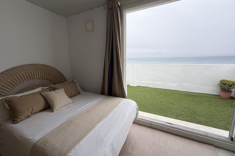 Dormitorio con cama doble y salida directa a terraza con vistas al mar en Infinity.