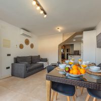 Salón comedor del apartamento Las Gaviotas 9B en Tarifa con mesa para cuatro personas, sofá y cocina abierta al fondo.