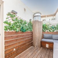 Terraza privada del Apartamento Las Gaviotas Nº9A con suelo de madera, banco con cojines y vegetación decorativa.