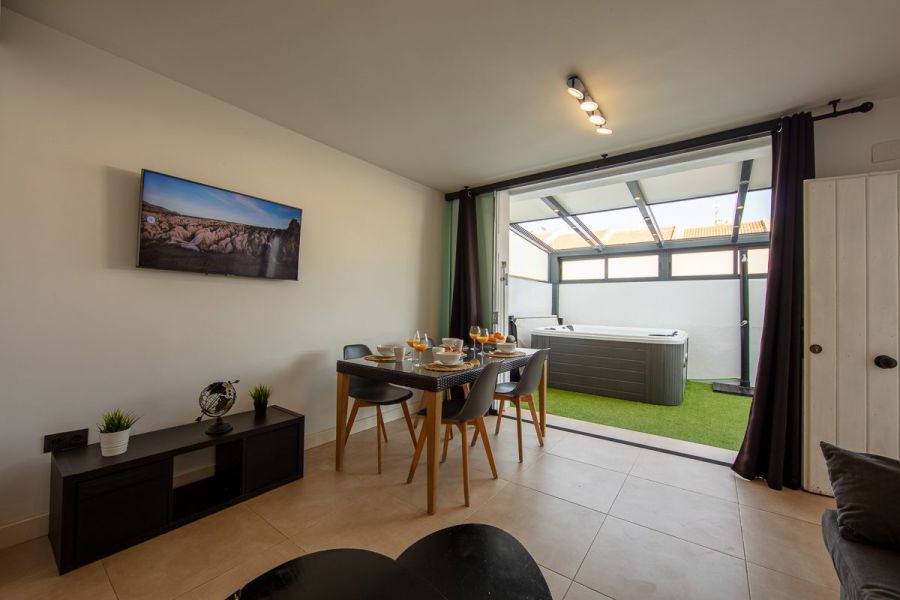 Salón comedor del apartamento Las Gaviotas 9B en Tarifa con mesa de comedor y vistas directas al patio con jacuzzi privado.