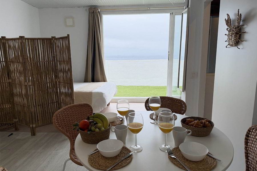 Salón comedor con sofá cama y vistas al mar en apartamento Infinity en Tarifa.